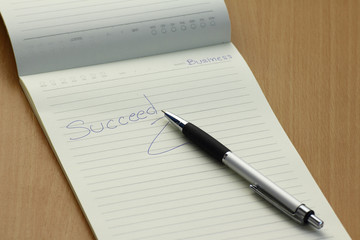 Pen and business plan notebook on wooden desk