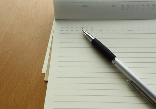 Pen and business plan notebook on wooden desk