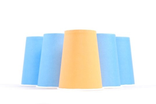 blue recycling paper glasses and one orange standing out on whit