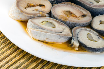 Rolls from a herring on a plate, on a straw support..