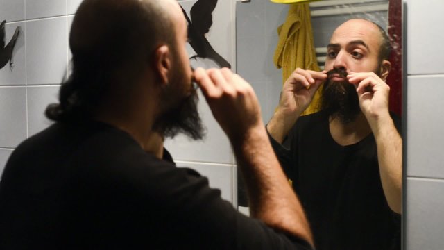 long beard and mustache man shaving in bathroom