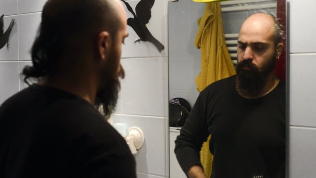 long beard and mustache man shaving in bathroom