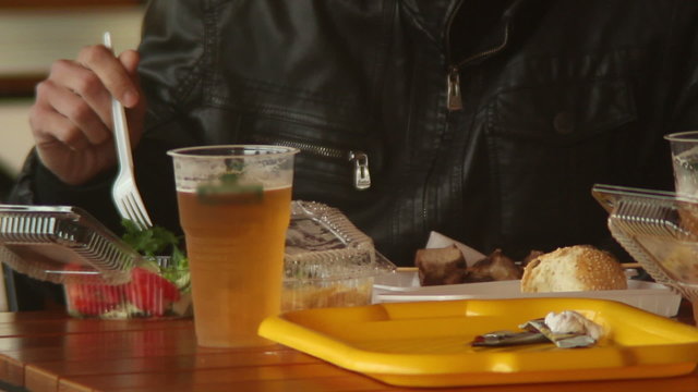 Man eating in fast food, drinking beer, plastic fork, burgers