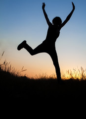 Silhouette of girl jumping in field