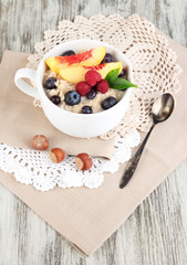 Oatmeal in cup with berries on napkins on wooden table