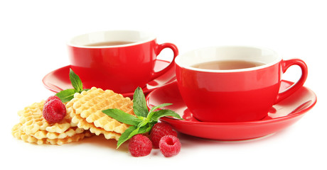 Cups of tea with cookies and raspberries isolated on white