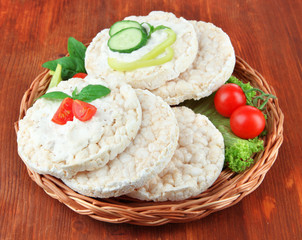 Tasty crispbreads with vegetables on wooden background