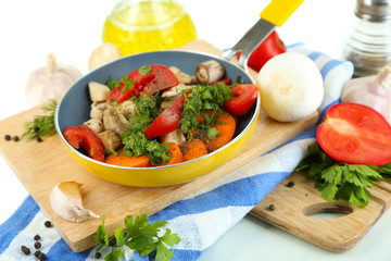 Sliced fresh vegetables in pan on wooden board isolated on