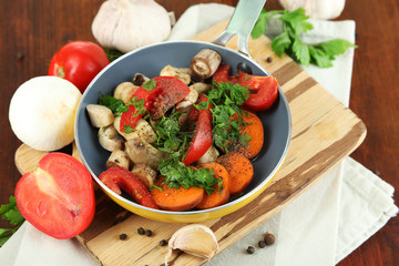 Sliced fresh vegetables in pan on wooden table close-up