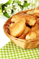 Tasty croissants in wicker basket on table on white background