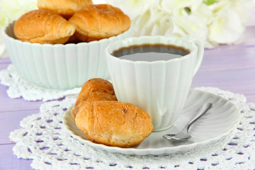 Tasty croissants and cup of coffee on table close-up