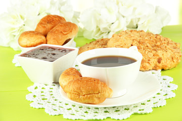 Tasty croissants and cup of coffee on table close-up