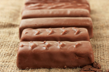 Delicious chocolate bars on sackcloth background