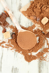 Cocoa powder in spoon on wooden table
