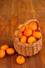 Small tangerines in wicker basket on wooden background