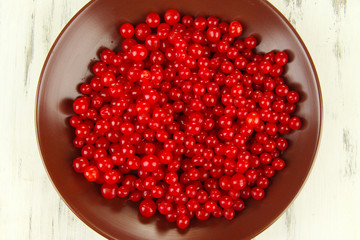 Red berries of viburnum in bowl on wooden background