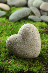 Grey stone in shape of heart, on grass background