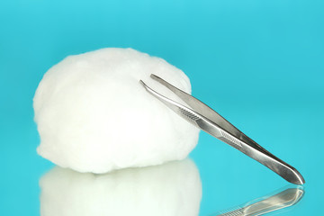 Wadding with tweezers on blue background