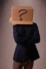 Young man gesturing with a cardboard box on his head with questi