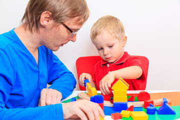 Father and son playing with colorful blocks at home