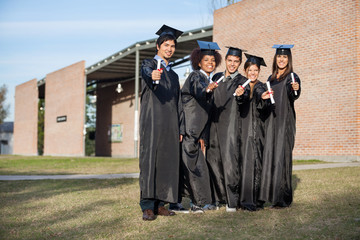 College Students Showing Diplomas Standing On Campus