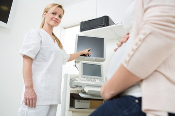 Fototapeta na wymiar Gynecologist Showing Ultrasound Scan To Pregnant Woman
