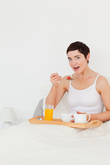 Fototapeta premium Portrait of a cute woman eating cereal while looking at the came