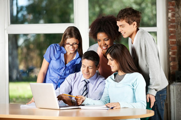 Fototapeta premium Professor With Laptop Explaining Students In Classroom
