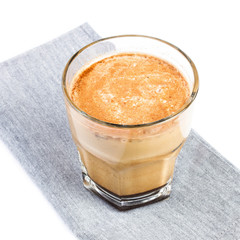 Coffee with milk  in a glass cup on linen tablecloth isolated on