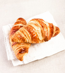 Fresh Croissants on a white linen napkin on beige tablecloth  ba