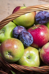 plums and apples in a wicker basket