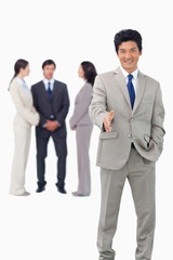 Salesman with team behind him offering hand