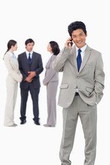 Businessman on cellphone with team behind him