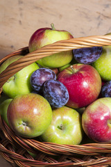 plums and apples in a wicker basket