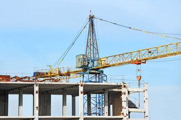 Crane and building construction site against blue sky