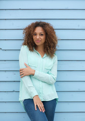 Happy young woman standing outdoors against blue background