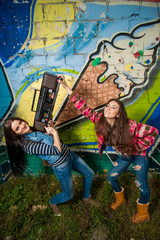 Two young girls with recorder in front of graffiti