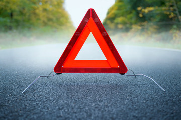Caution fog - Warning triangle on a foggy road.