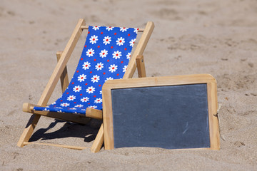 Strandliege und eine Schiefertafel am Strand