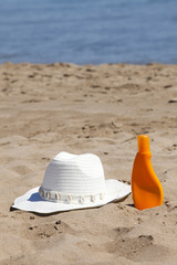 Fototapeta na wymiar Słomkowy kapelusz i krem ??słońce na plaży
