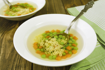 Soup with star shaped noodles, carrots and green peas