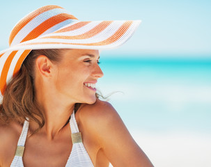 Portrait of happy young woman in swimsuit and beach hat 