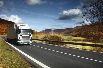 White truck driving through autumn landscape 