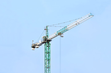 Green construction tower crane against blue sky