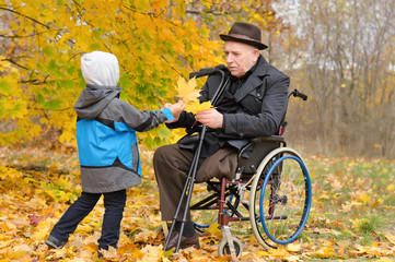 Young child giving an elderly man autumn leaves
