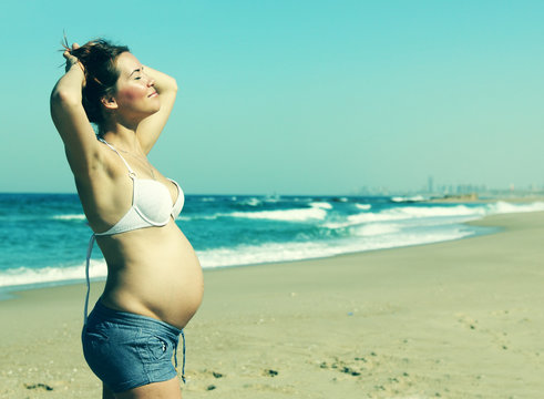 beautiful pregnant woman standing on the beach. Photo in old ima