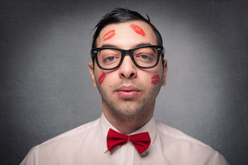 Portrait of young nerd with kiss imprints isolated on grunge bac
