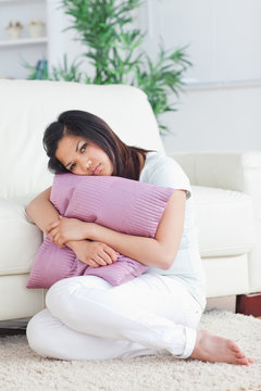 Woman looking sad while holding a pillow