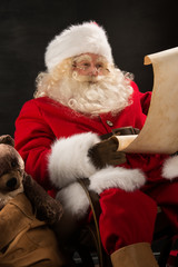Portrait of Santa Claus reading big letter on old paper roll