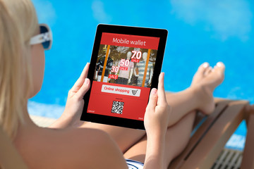 girl lying on a sun lounger by the pool with a tablet and onlain